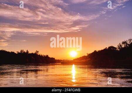 Atmosfera magica di una serata romantica; tramonto dorato sul fiume Foto Stock