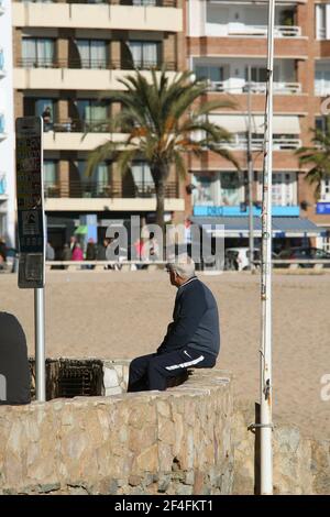 Un visitatore maturo sedette vicino alla spiaggia in riva al mare Città di Lloret de Mar sulla Costa Brava vicino Calella in Catalogna Spagna EU 2019 Foto Stock