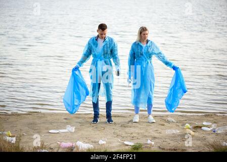 Volontari che raccolgono bottiglie di plastica in sacchetto di spazzatura, ecologia, natura, inquinamento, rifiuti, cura, volontariato di beneficenza, ambiente di comunità. Foto Stock