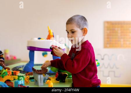 Il ragazzo prescolare immerso in un gioco con un costruttore Foto Stock