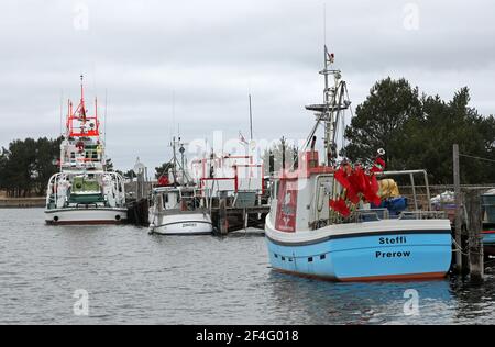 Prerow, Germania. 16 Marzo 2021. L'incrociatore di salvataggio Theo Fischer del servizio tedesco di ricerca e salvataggio marittimo (DGzRS) e le imbarcazioni da pesca sono ormeggiate nel porto di rifugio Darßer Ort nella zona centrale del parco nazionale Vorpommersche Boddenlandschaft. Credit: Bernd Wüstneck/dpa-Zentralbild/ZB/dpa/Alamy Live News Foto Stock