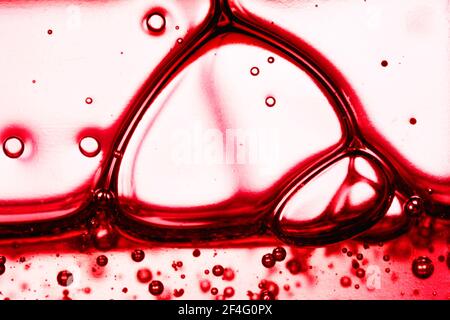 Bolle di sapone liquido rosso. Olio sulla superficie della schiuma di sapone. Vista macro astratta della struttura delle molecole del sangue. Profondità superficiale dell'immagine di campo Foto Stock