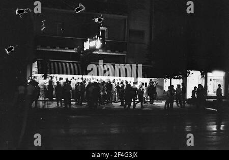 Vista notturna di un gran numero di clienti che si trovano fuori da una gelateria a Vedado, l'Avana, Cuba, 1964. Dalla collezione di fotografie Deena Stryker. () Foto Stock