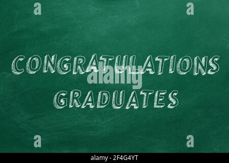 Testo di disegno a mano 'Congratulazioni laureati' sulla lavagna verde. Foto Stock