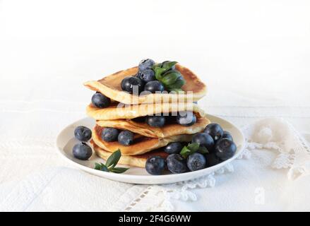 Deliziosi pancake con mirtilli freschi e miele sul tavolo. Sfondo bianco. Foto Stock