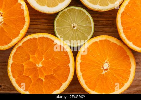 Arance, lime e limoni scivoli su tavola di legno vista da sopra.Beautiful Sfondo con frutta fresca metà cut.Healthy mangiare vitamina C.Summer tropica Foto Stock