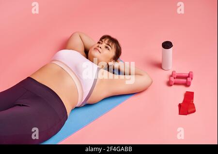 Donna sovrappeso giacente sul tappetino, corpo positivo Foto Stock