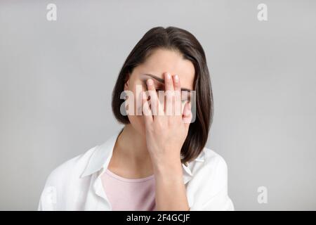 Espressioni ed emozioni del volto umano. Ritratto di giovane bruna multietnica donna palma viso in canotta rosa e camicia bianca. Foto Stock