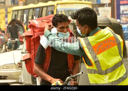 Dhaka. 21 Mar 2021. Un poliziotto dà una maschera ad un estrattore di risciò su una strada a Dhaka, Bangladesh, 21 marzo 2021. Il governo del Bangladesh sottolinea l'uso di maschere per contenere la diffusione della pandemia COVID-19. Credit: Xinhua/Alamy Live News Foto Stock