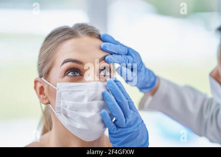 Occhio-medico in maschera di controllo su paziente femminile Foto Stock