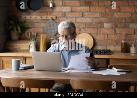 Pensieroso uomo anziano serio fornire il pagamento di ipoteca in linea sul pc Foto Stock