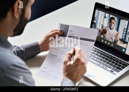 Datore di lavoro indiano che legge cv durante l'intervista virtuale di lavoro con il candidato africano. Foto Stock