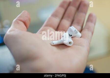 Primo piano cuffie wireless bluetooth o auricolari sul palmo della donna. Foto Stock