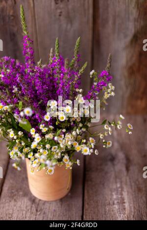 Un bouquet di fiori selvatici. Estate fiore selvaggio. Sfondo e tavolo in legno. Posiziona per il testo. Piccolo Phalacrol e Veronica spicata. Spazio di copia Foto Stock