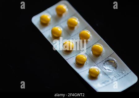 Compresse gialle in blister su sfondo nero Foto Stock