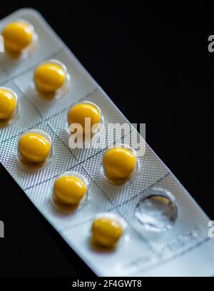 Compresse gialle in blister su sfondo nero Foto Stock