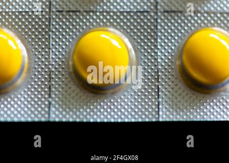 Compresse gialle in blister su sfondo nero Foto Stock