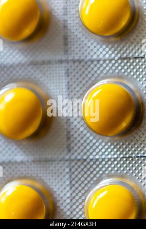 Compresse gialle in blister su sfondo nero Foto Stock