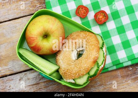 Sano pranzo al sacco composto da bagel con formaggio spalmabile, cetrioli e pomodori ciliegini Foto Stock