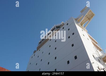 Vista sulla sovrastruttura bianca con ponte di navigazione della nave mercantile container dal ponte principale durante il giorno di sole con cielo blu e azzurro. Foto Stock