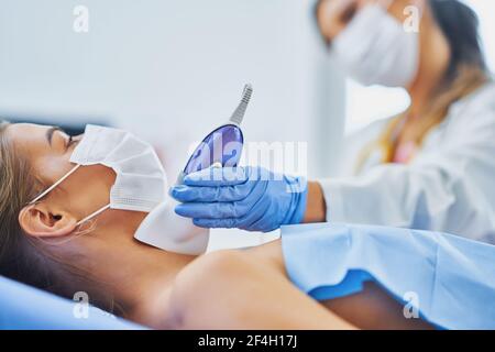 Medico in maschera controllo tiroide alla sua paziente femminile Foto Stock