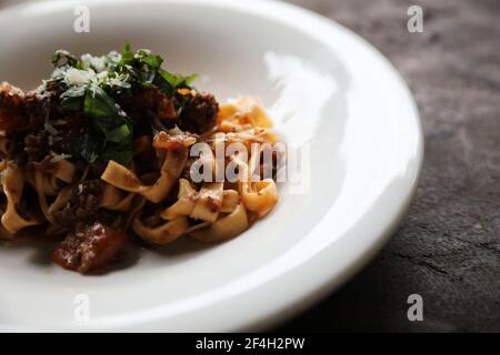 Pasta fettuccine bolognese con salsa di manzo e pomodoro su legno sfondo in tonalità scure stile mistico chiaro Foto Stock