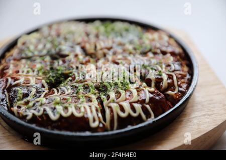 Il cibo giapponese okonomiyaki , Giapponese pizza sul piatto di legno Foto Stock