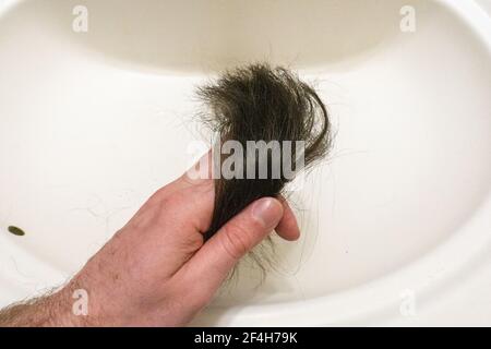 Dopo la rasatura, tenere in mano i ciocche di capelli nel lavandino testa Foto Stock