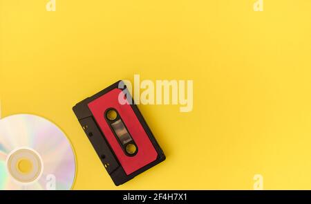 Cassetta audio nera e disco su sfondo giallo. 80 s. Vista dall'alto. Disposizione piatta. Foto Stock