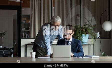 Diversi dipendenti di sesso maschile si scambiano idee per lavorare su un computer portatile Foto Stock