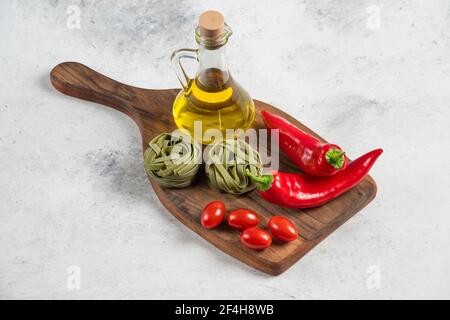 Tagliatelle verdi, ortaggi e olio d'oliva su tavola di legno Foto Stock