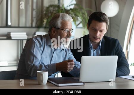 Diversi dipendenti di sesso maschile collaborano utilizzando il computer in ufficio Foto Stock