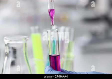 Il liquido viola viene lasciato cadere dalla pipetta nella provetta Foto Stock