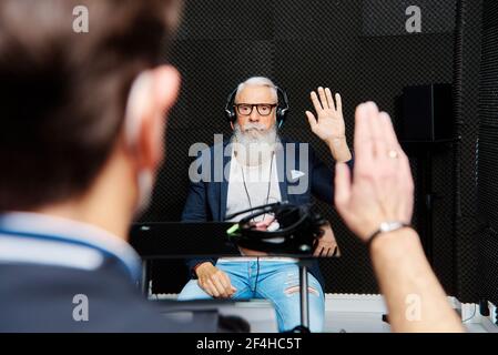 Anziano ha sopportato il maschio nelle cuffie seduto in stanza insonorizzata durante esame audiologico e test uditivo Foto Stock