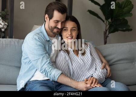 Felice giovane coppia amorevole abbracciando, rilassandosi insieme sul divano Foto Stock