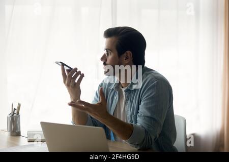 Vista laterale uomo d'affari sicuro indossare occhiali registrazione messaggio vocale Foto Stock