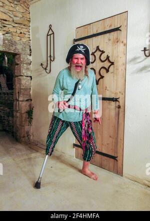 L'uomo più anziano, porticato, manca la gamba inferiore destra usando la sua disabilità per vestirsi come un pirata. Foto Stock
