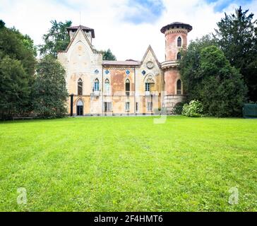 ITALIA, MIRADOLO - CIRCA AGOSTO 2020: Castello di design gotico situato in un giardino all'italiana, pieno di mistero, con luce del tramonto. Foto Stock