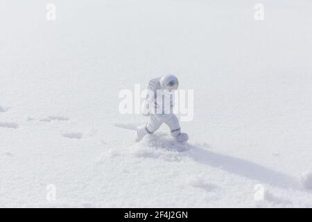 La statuetta di un astronauta esplora con sicurezza la superficie del pianeta alieno. Pianeta freddo coperto di neve. Spazio di copia. Foto Stock