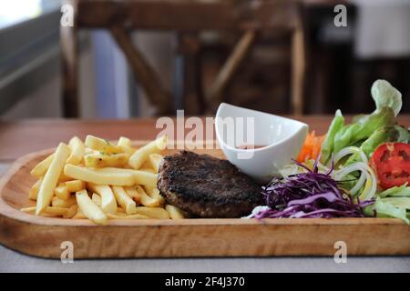 Cotoletta di manzo per bistecca con fuochi e verdure su legno sfondo Foto Stock