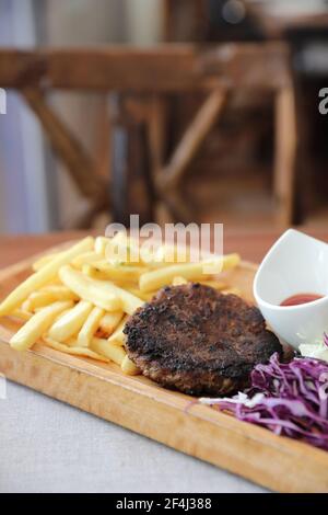 Cotoletta di manzo per bistecca con fuochi e verdure su legno sfondo Foto Stock