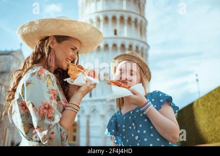 Sorridente madre e figlia moderna con la pizza vicino alla Torre Pendente a Pisa, Italia. Foto Stock