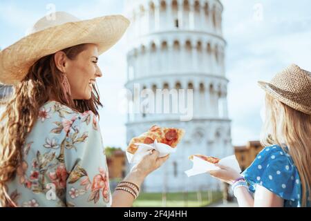 Sorridente madre e figlia alla moda con la pizza vicino alla Torre Pendente a Pisa, Italia. Foto Stock