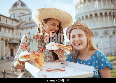 Sorridente elegante madre e bambino con pizza vicino alla Torre Pendente a Pisa, Italia. Foto Stock