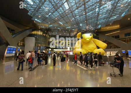 Interno del terminal dell'aeroporto internazionale di Doha Hamad con più passeggeri che si collegano durante la pandemia utilizzando maschere. Terminal passeggeri a Doha, Qatar. Foto Stock