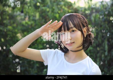 Ritratto bella ragazza asiatica in verde foglie sfondo Foto Stock