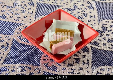 Caramelle alla fragola e alla liquirizia in involucri di caramelle in caramelle rosse piatto su pizzo Foto Stock