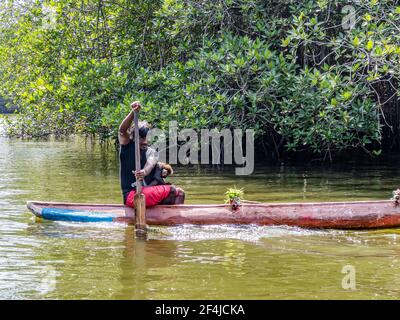 BENTOTA, SRI LANKA - 14 NOVEMBRE 2019: Ritratto di un residente locale con una scimmia su una barca sul fiume Bentota Ganga nella giungla sull'isola di Foto Stock