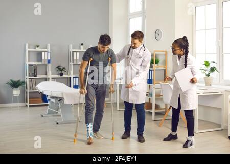 Team di medici di diverse nazionalità in ospedale aiuta il loro paziente con una caviglia rotta. Foto Stock