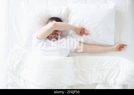 Un uomo adulto dorme in camera da letto su un grande letto Foto Stock